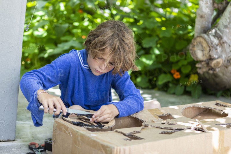 Boy cutting a cardboard box