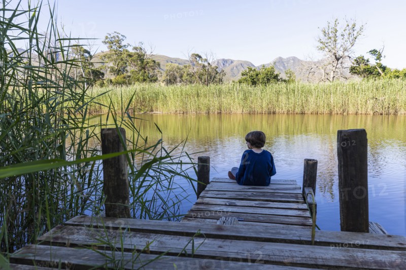 Boy sitting on wooden pier