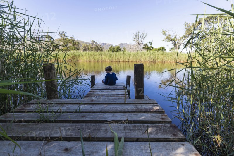 Boy sitting on wooden pier