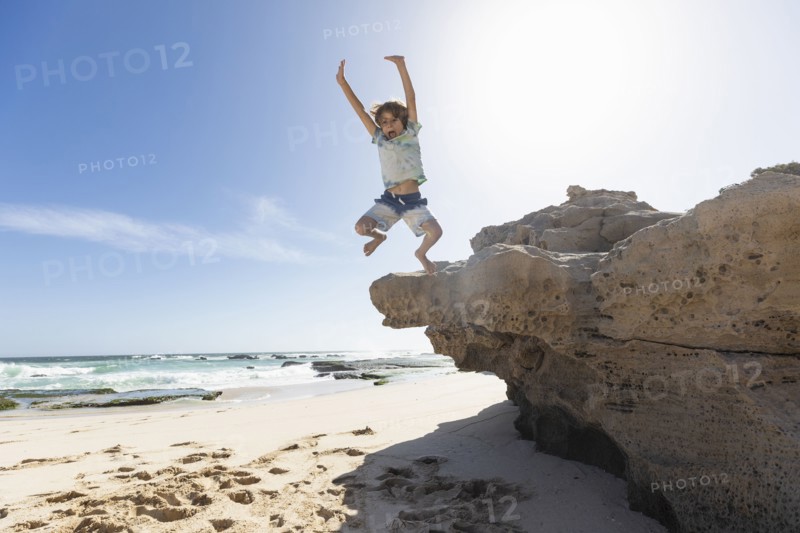 Boy jumping off rock