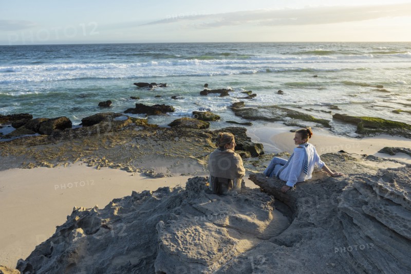 Mother and daughter sitting on beach