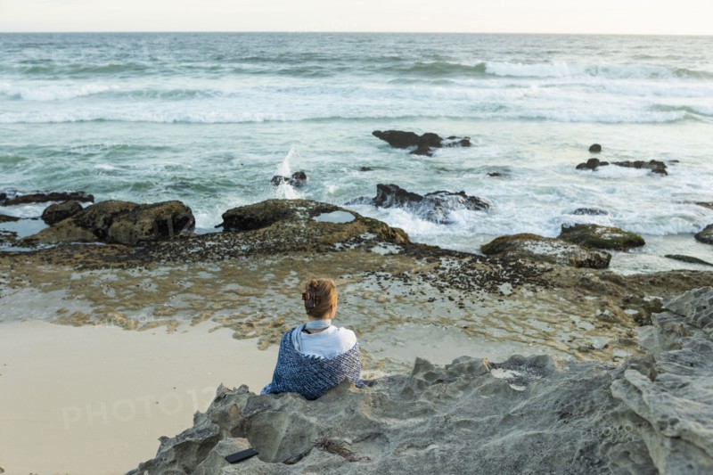 Girl sitting on beach looking at ocean