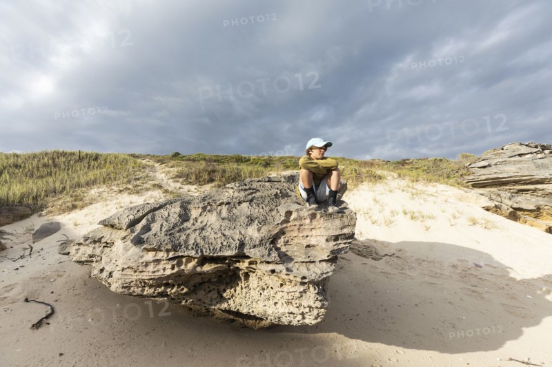 Boy sitting on beach rock