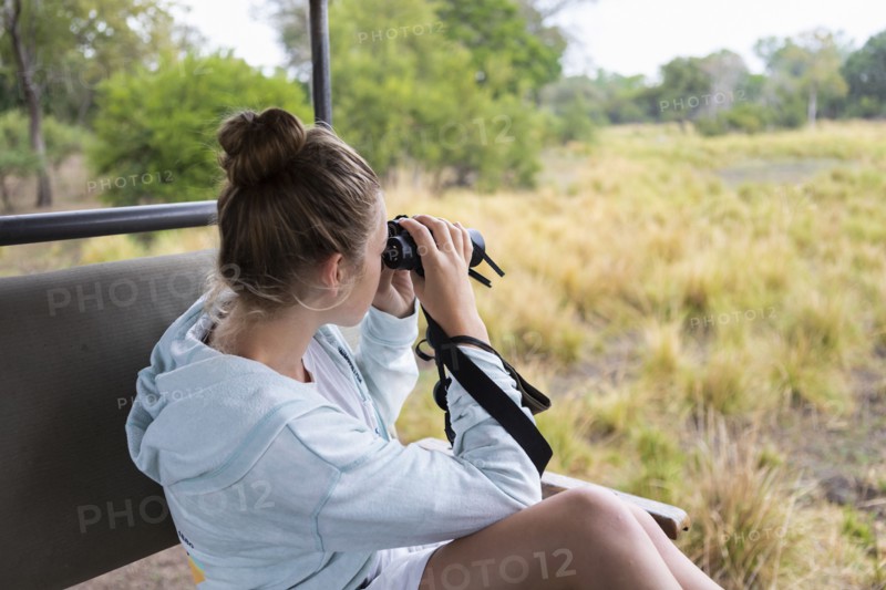 Girl in safari vehicle using binoculars