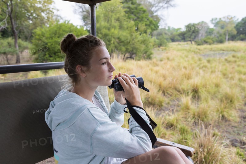Girl in safari vehicle using binoculars