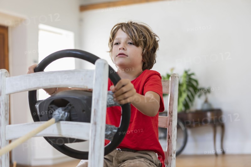 Boy playing with steering wheel in living room