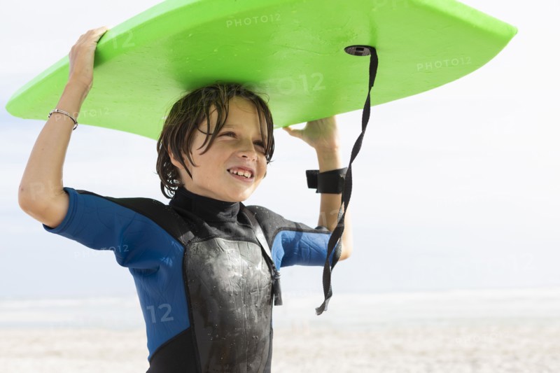 Boy carrying bodyboard on beach