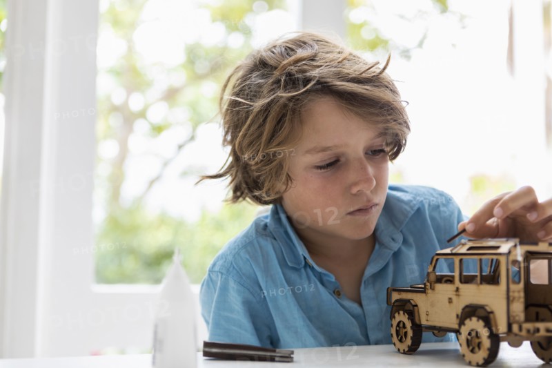 Boy building wooden toy car at home