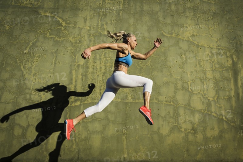 Athlete woman jumping against wall