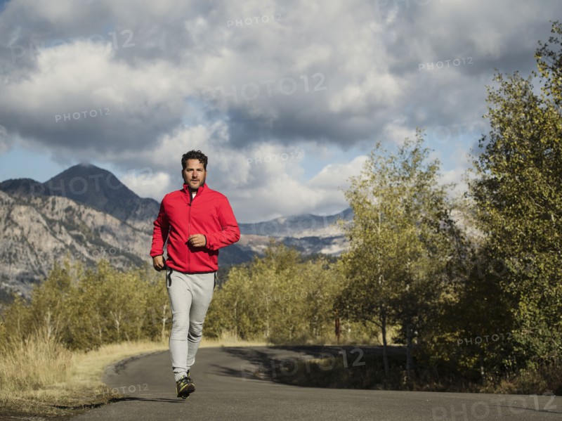 Man jogging on mountain road on sunny day