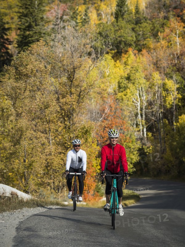 Smiling man and woman riding bicycles on country road