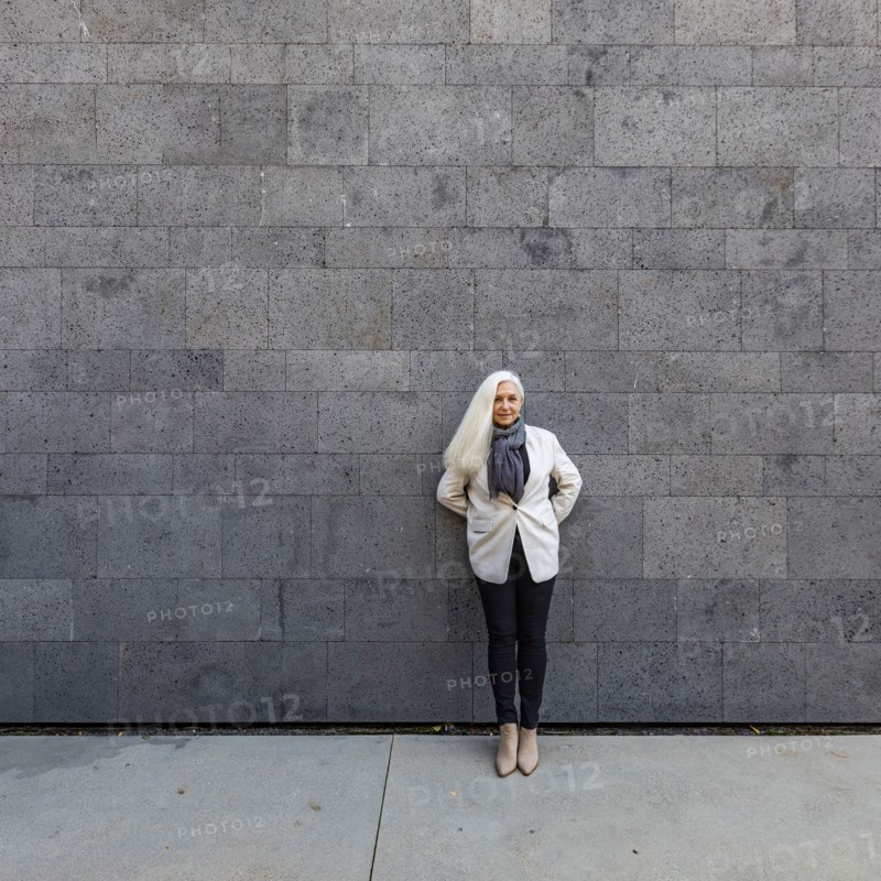 Portrait of senior woman leaning against wall