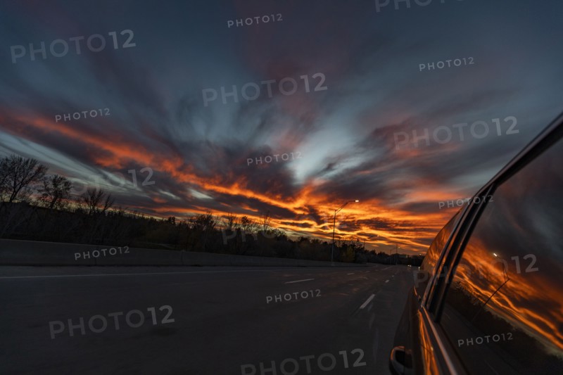 Sunset reflected in side window of car driving on freeway