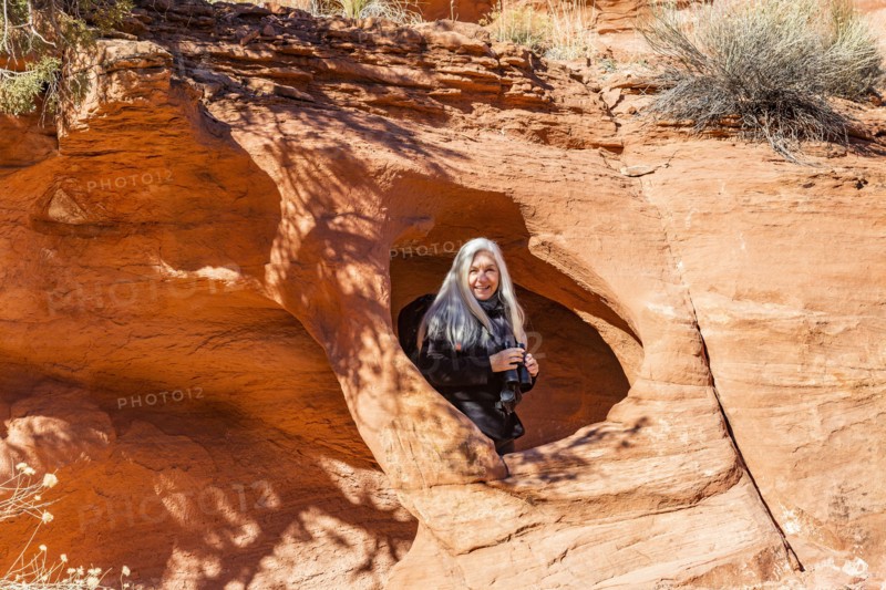 Senior hiker standing in rock opening in sandstone cliff