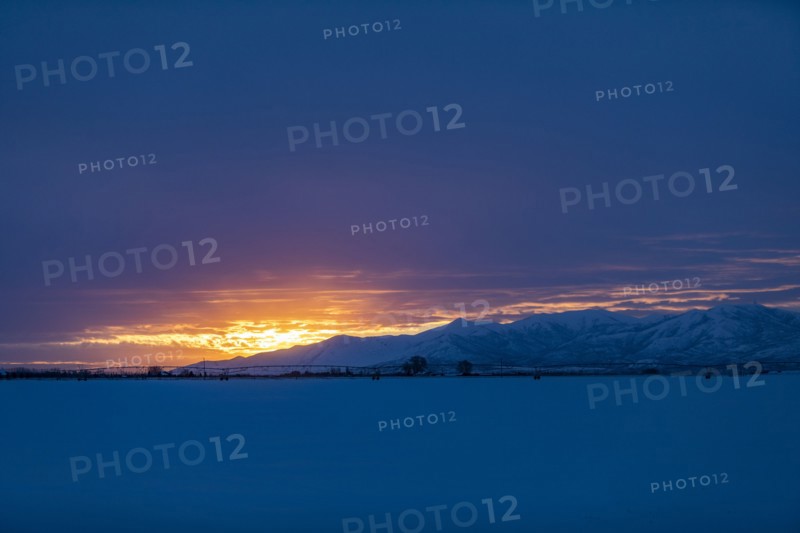 Sun rising above snowcapped mountains