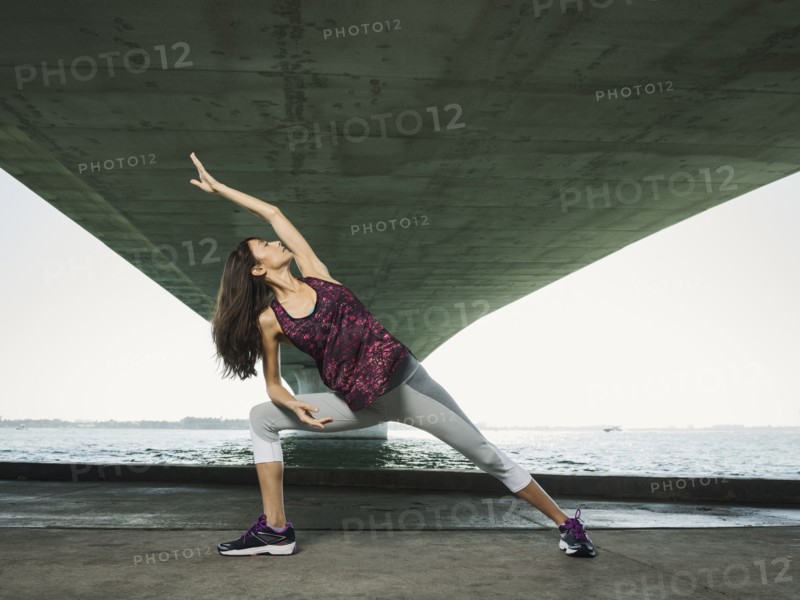 Woman stretching under bridge