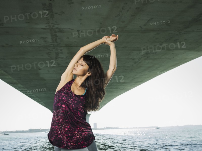 Woman stretching under bridge