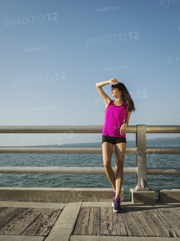 Woman in sport clothing standing on bridge on sunny day