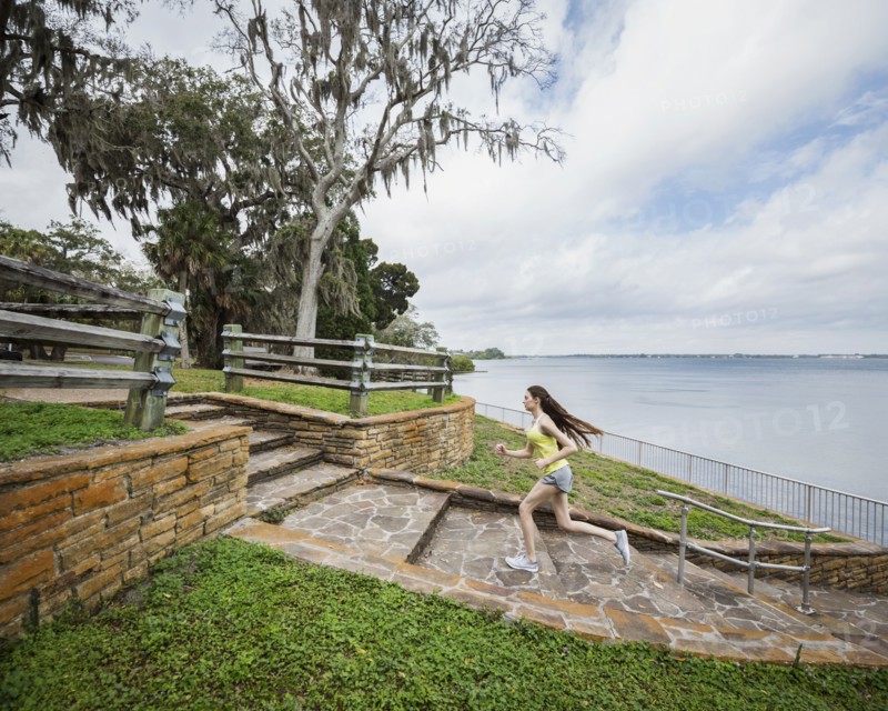Athlete woman running up steps by river
