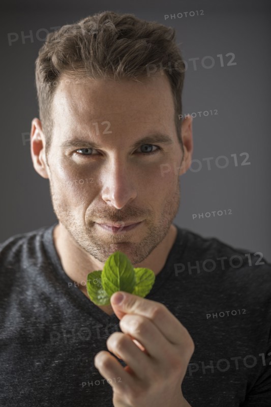 Studio portrait of man holding fresh mint leaves