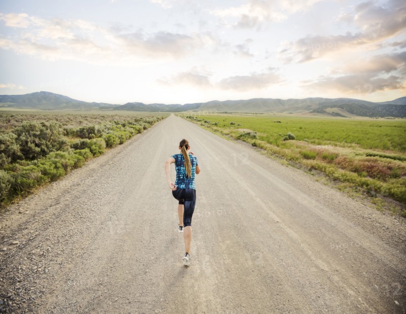 Rear view of woman jogging on road in desert landscape