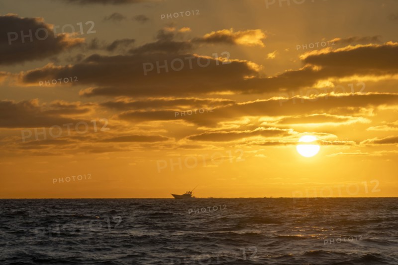 Small fishing boat in ocean at sunrise