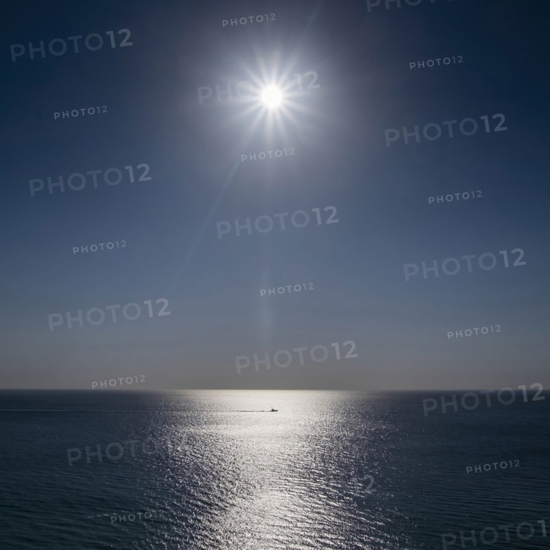 Sun shining above calm ocean surface