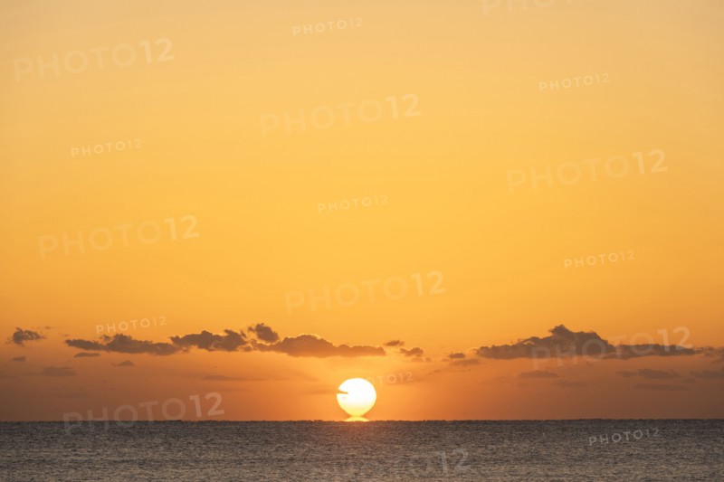 Sun rising above calm ocean