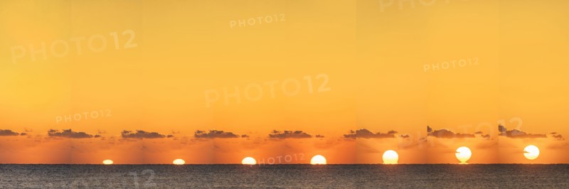 Sequential sun rising above calm ocean