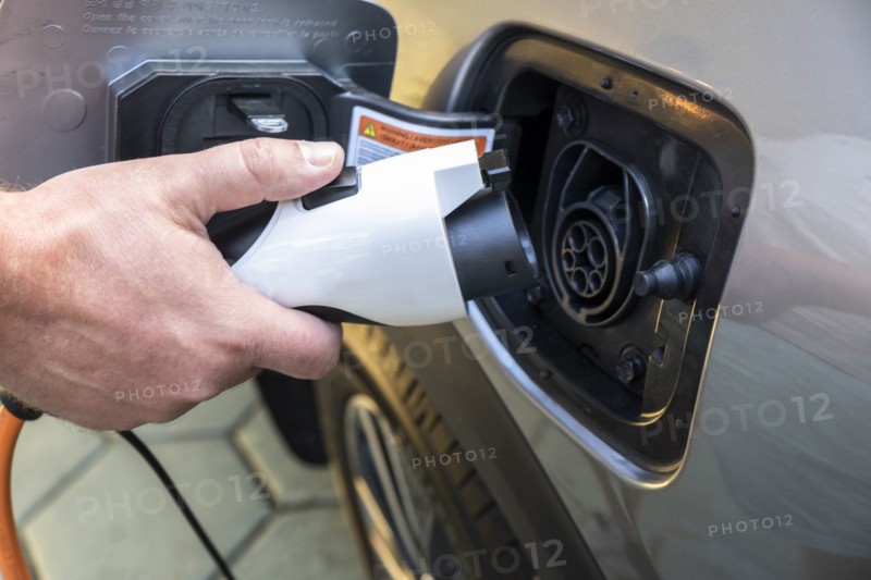 Mans hand holding charge cable in electric vehicle