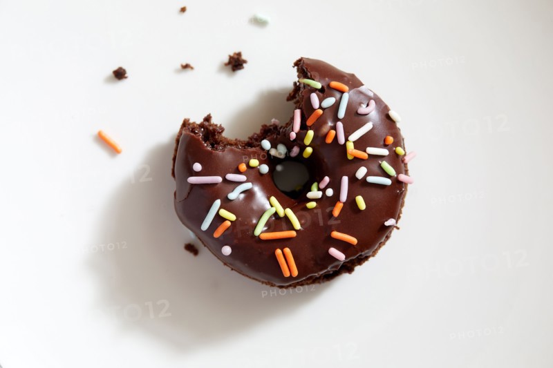 Overhead view of partially eaten donut with chocolate icing and sprinkles