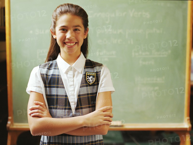 Portrait of girl (10-11) standing in front of chalkboard