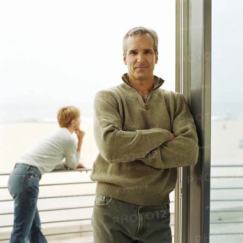 Portrait of man leaning on doorway of house