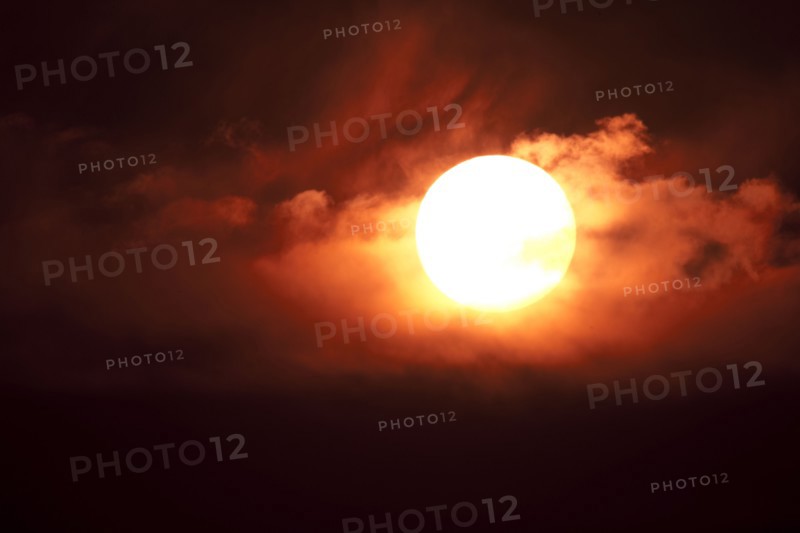 Dramatic sun with orange clouds in sunset sky