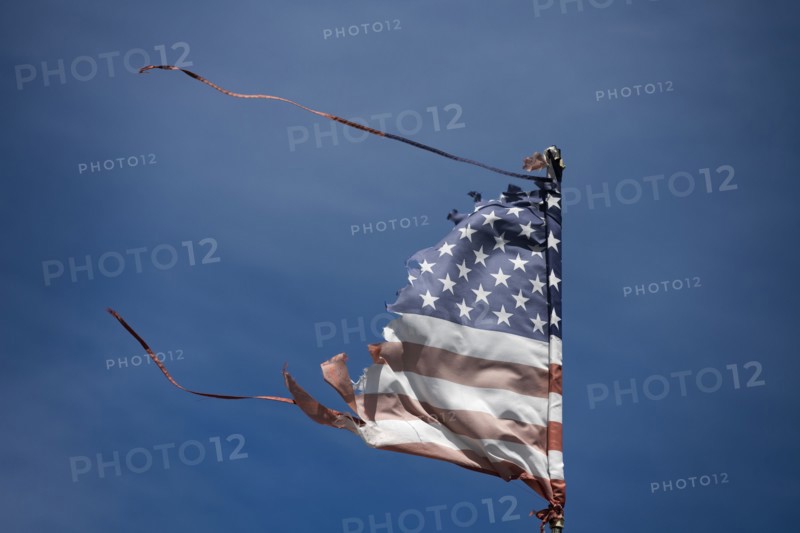 Worn and wind-torn American flag blowing against blue sky