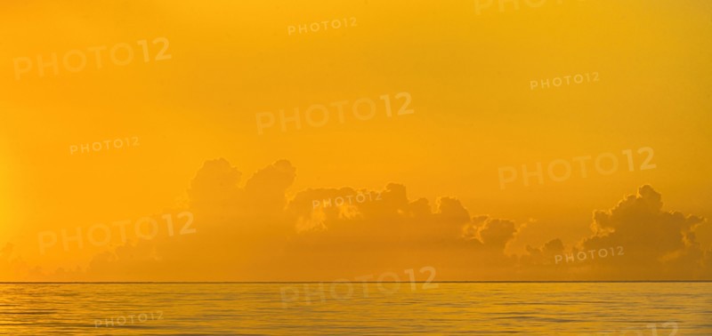 Golden sunrise clouds over calm ocean