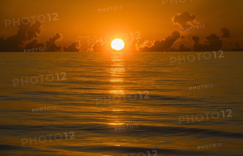 Sun rising above calm ocean