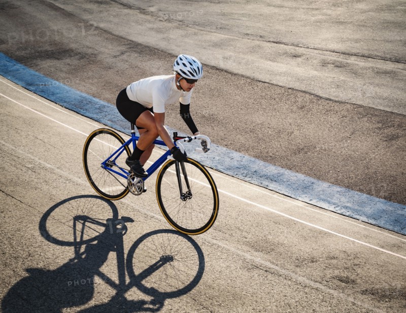 Athletic woman with amputated hand cycling on track