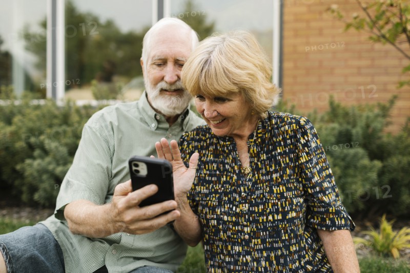 Smiling senior couple having video call in back yard