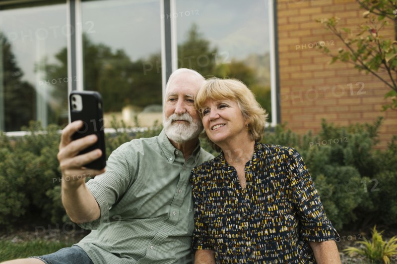 Smiling senior couple taking selfie in backyard