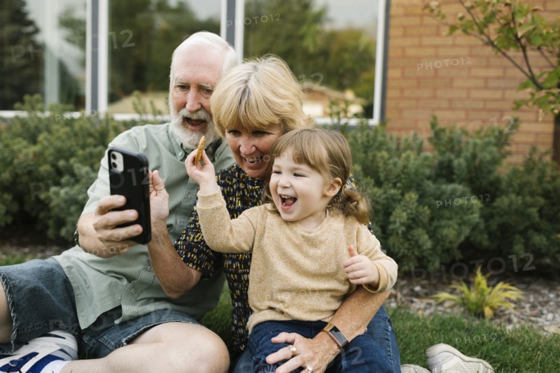 Smiling grandparents taking selfie with granddaughter