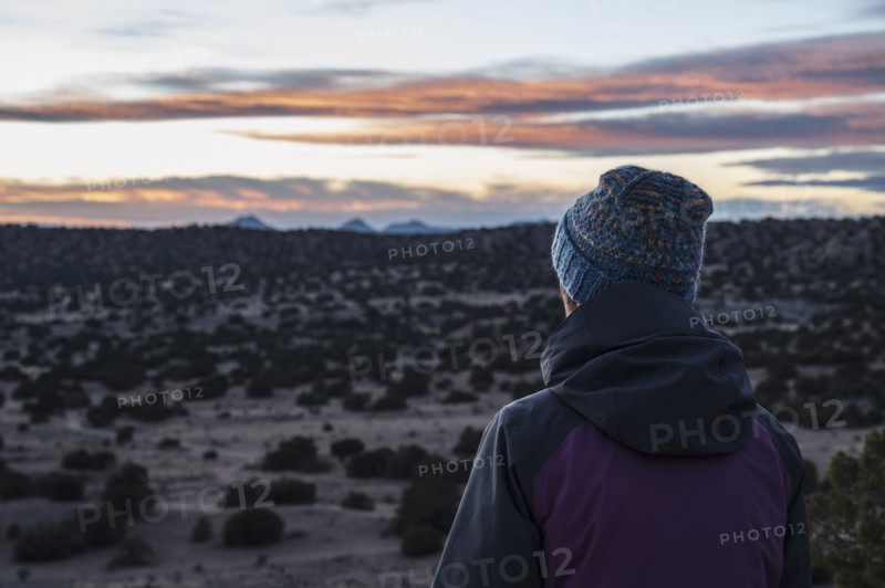 Rear view of woman in desert landscape at sunset