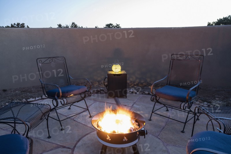Chairs around back yard fire pit at dusk