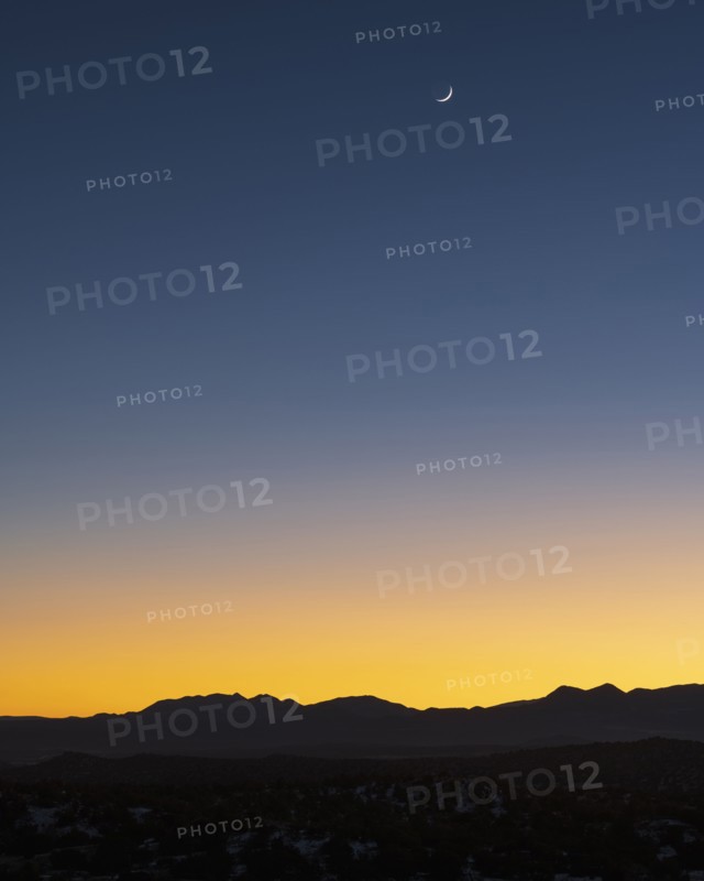 Jemez Mountains at dusk with crescent moon on sky