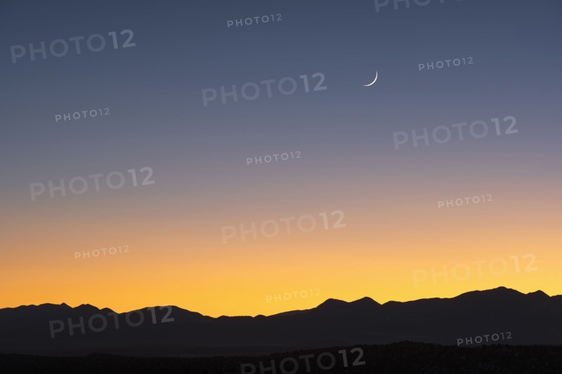 Jemez Mountains at dusk with crescent moon on sky
