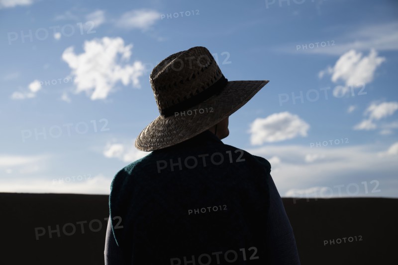 Rear view of woman in straw hat standing in desert landscape