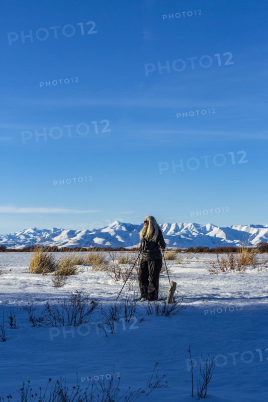 Senior blonde woman snow shoeing in snow covered landscape