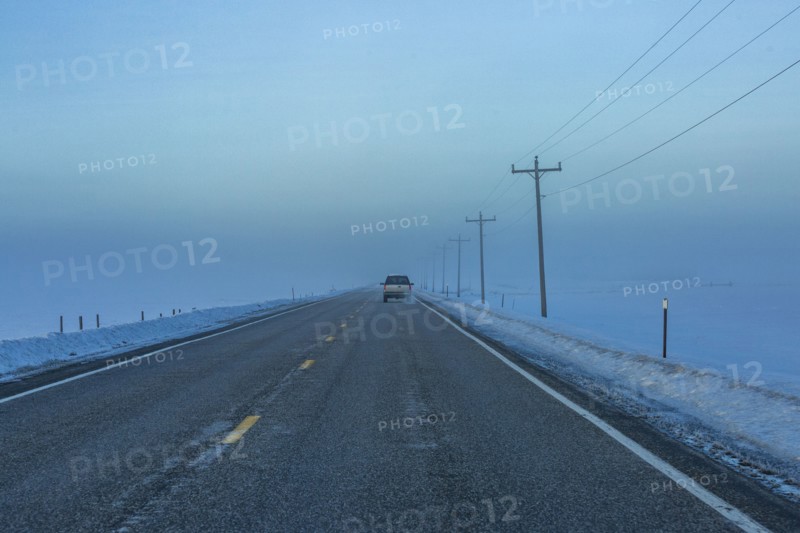 Car heading into fogbank along Highway 20 in winter