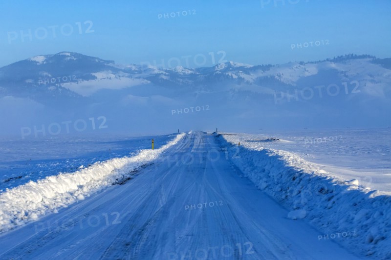 Snow covered rural road leading to mountains