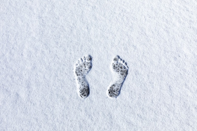 Overhead view of bare footprints in fresh snow